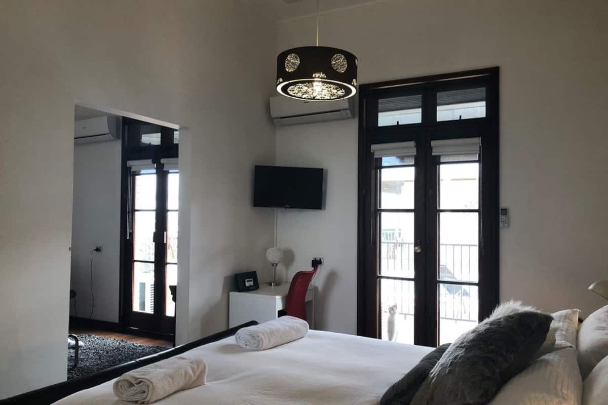 Ein Hotelzimmer mit einem großen Bett, einem Schreibtisch, einem Stuhl, einem Fernseher und einem Balkon mit Aussicht.