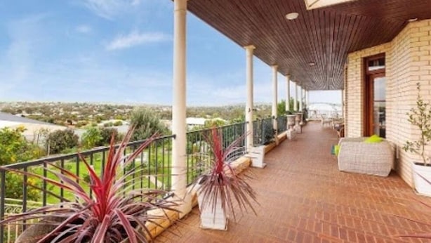 A covered outdoor balcony with a brick floor, potted plants, and a view of the surrounding landscape. - Fairway Manor Accommodation (Northam)