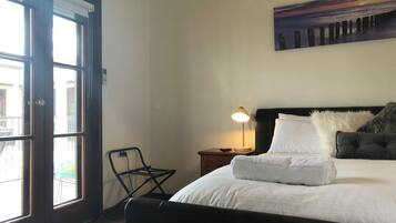 A hotel room with a bed, a nightstand, a lamp, a chair, and a painting on the wall.