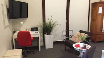 A compact office space with a desk, chair, and a television mounted on the wall.