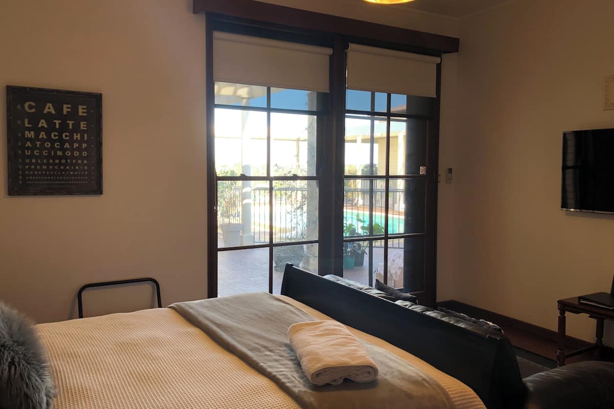 Ein Hotelzimmer mit Bett, Fenster mit Blick auf einen Pool, Fernseher und einem Schild an der Wand.