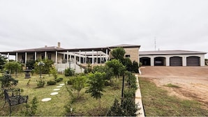 A large building with a covered patio area, a driveway, and a parking area with multiple garages. - Fairway Manor Accommodation (Northam)