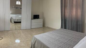 Una camera da letto con un letto, una cassettiera, una televisione, un condizionatore d'aria e un armadio.