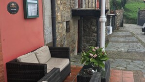 Un espace extérieur accueillant, aménagé avec des meubles en osier et agrémenté d’une plante en pot.