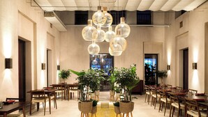 A spacious dining area with multiple tables and chairs, hanging pendant lights, and potted plants. - The Chedi Al Bait, Sharjah, UAE (Sharjah)