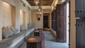 A hallway with a bench, decorative lighting, and a patterned rug. - The Chedi Al Bait, Sharjah, UAE (Sharjah)