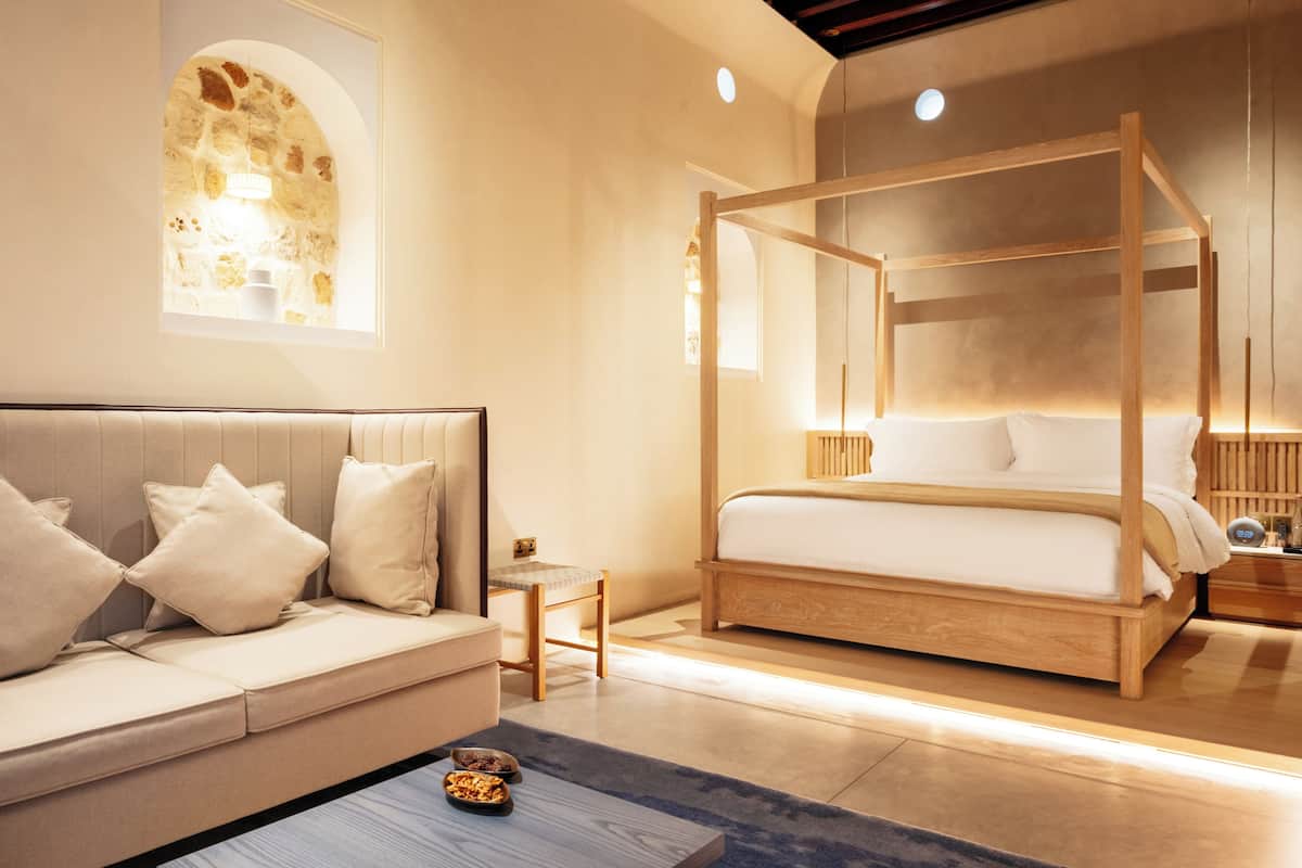 A modern bedroom with a four-poster bed, a sofa, and a small table.
