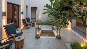 A modern outdoor seating area with lounge chairs, a small table, and a decorative water feature. - The Chedi Al Bait, Sharjah, UAE (Sharjah)