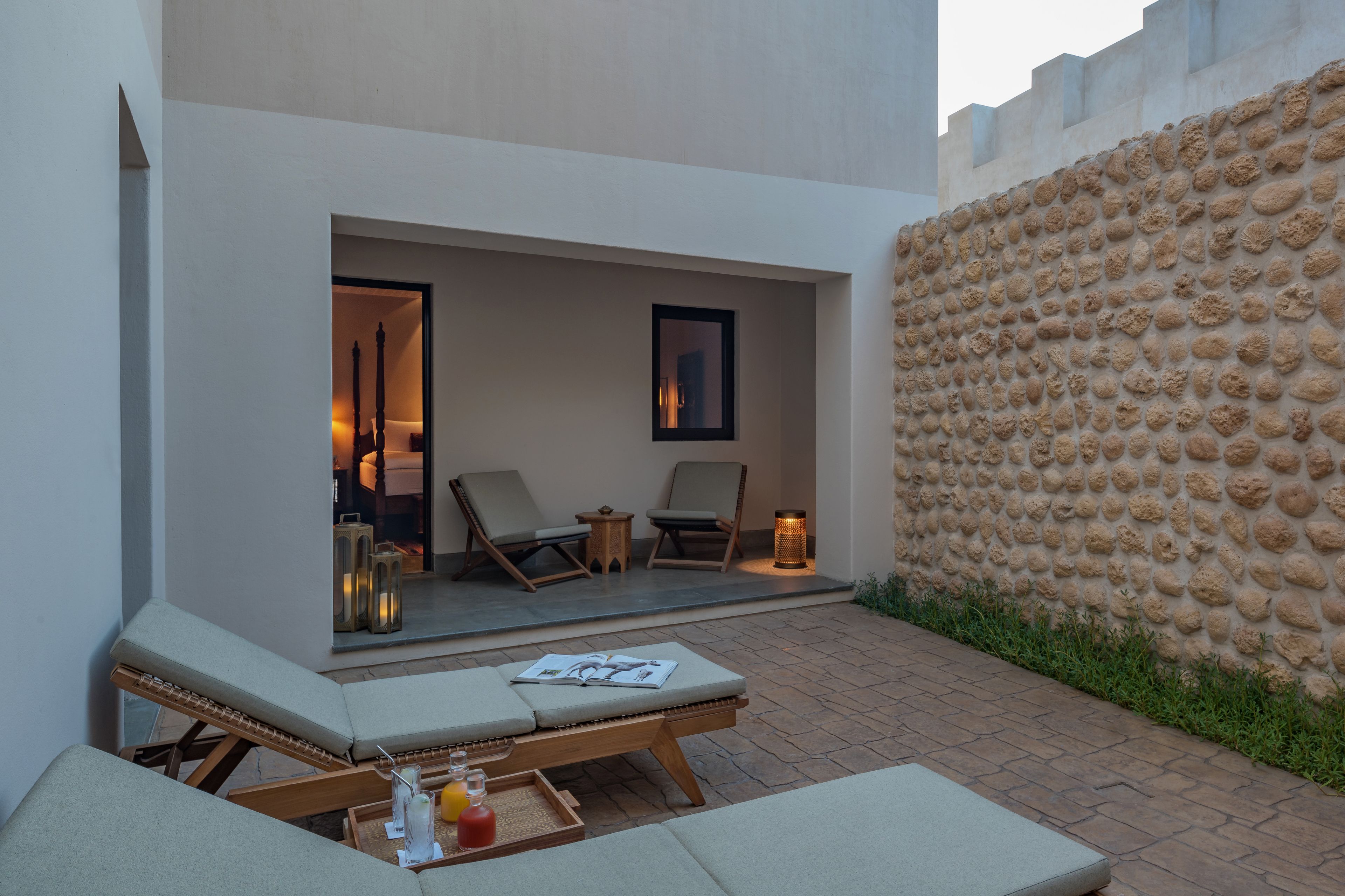 A modern outdoor lounge area with two lounge chairs, a small table, and a tray with bottles.