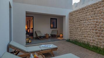 A modern outdoor lounge area with two lounge chairs, a small table, and a tray with bottles.
