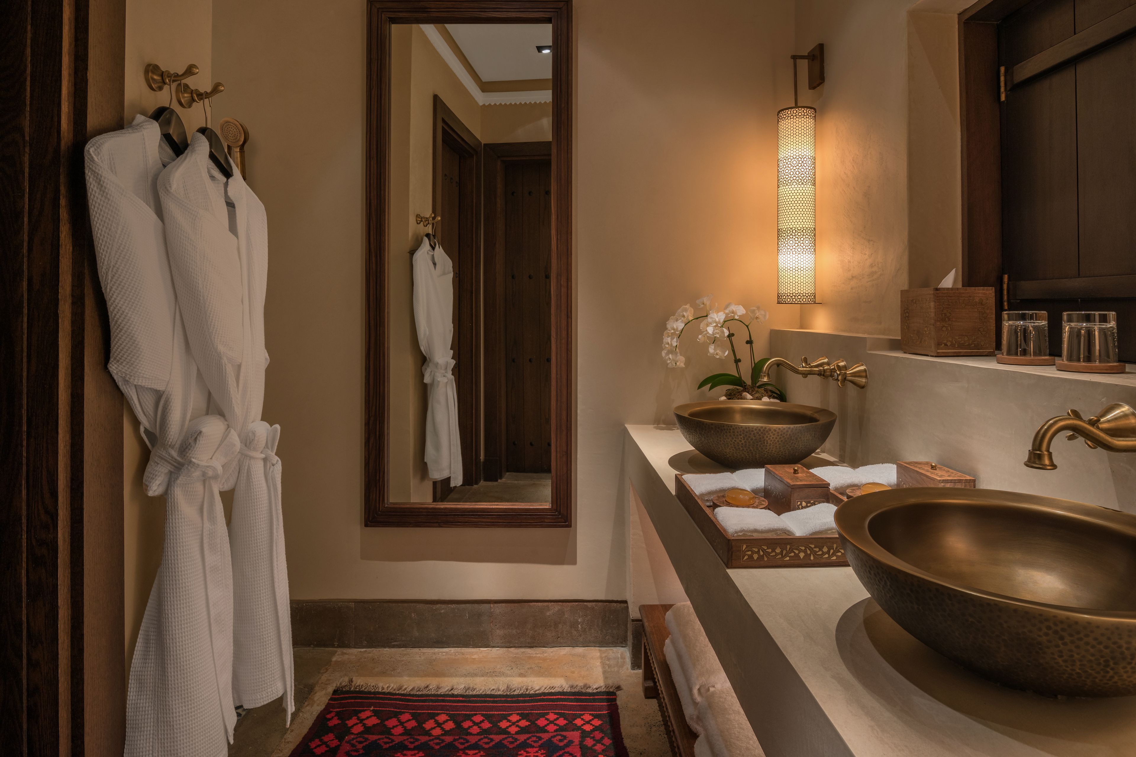 A bathroom with a large mirror, two sinks, and a towel rack.