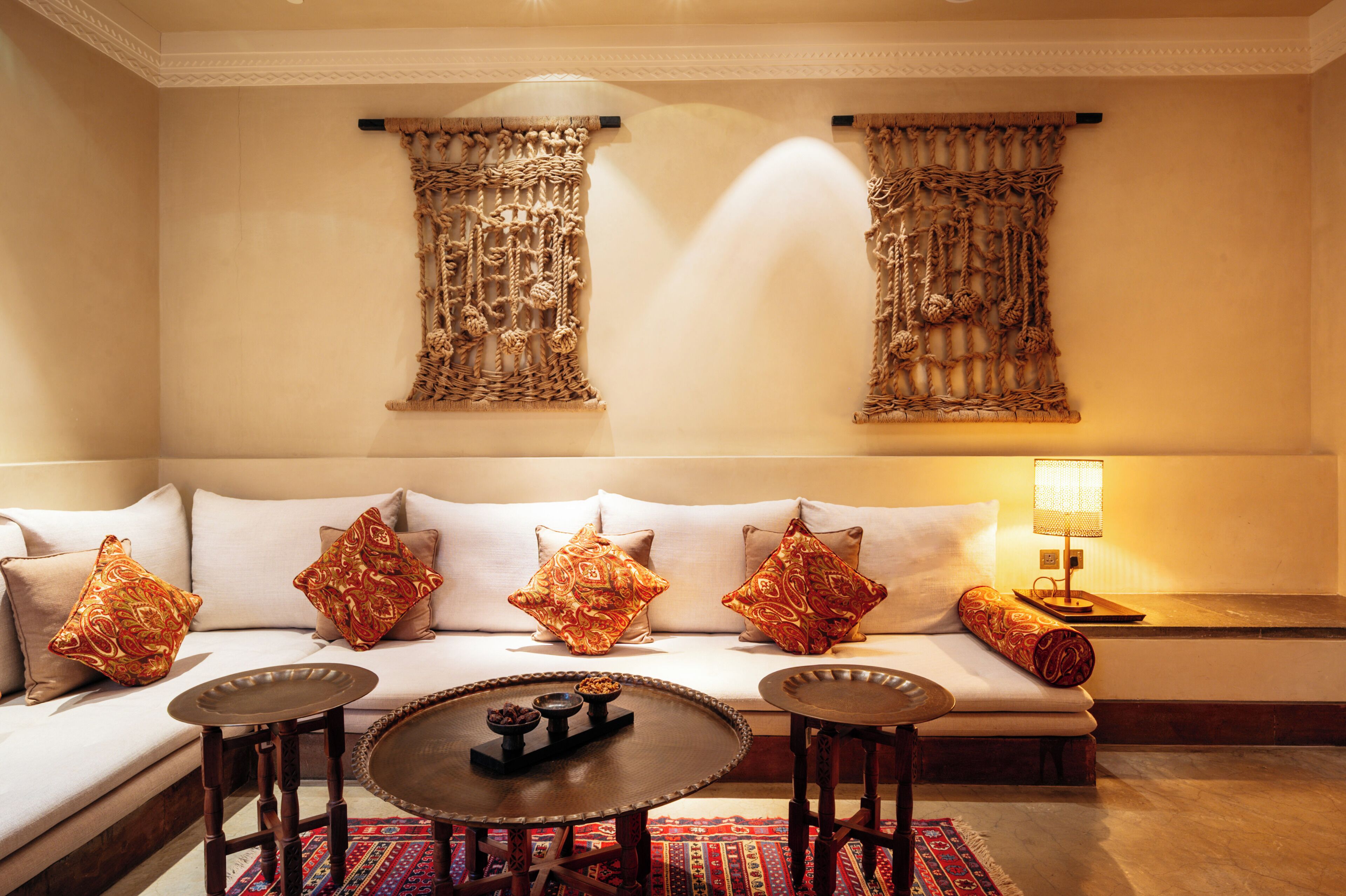 A modern living room with a sofa, decorative pillows, a round coffee table, and a small side table with a lamp.