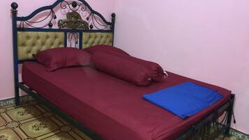 Una cama individual con cabecera, ropa de cama roja y una manta azul.