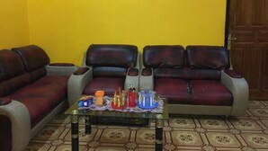 A living room with a sofa set, a coffee table with drinks, and a door in the background.