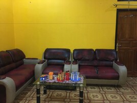 Una sala de estar con un conjunto de sofá, una mesa de centro con bebidas y una puerta al fondo.