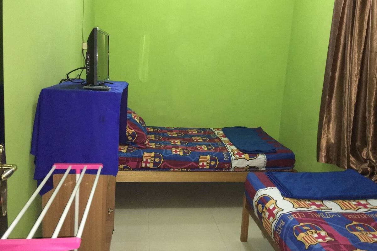 Una habitación pequeña con cama, escritorio y televisor.