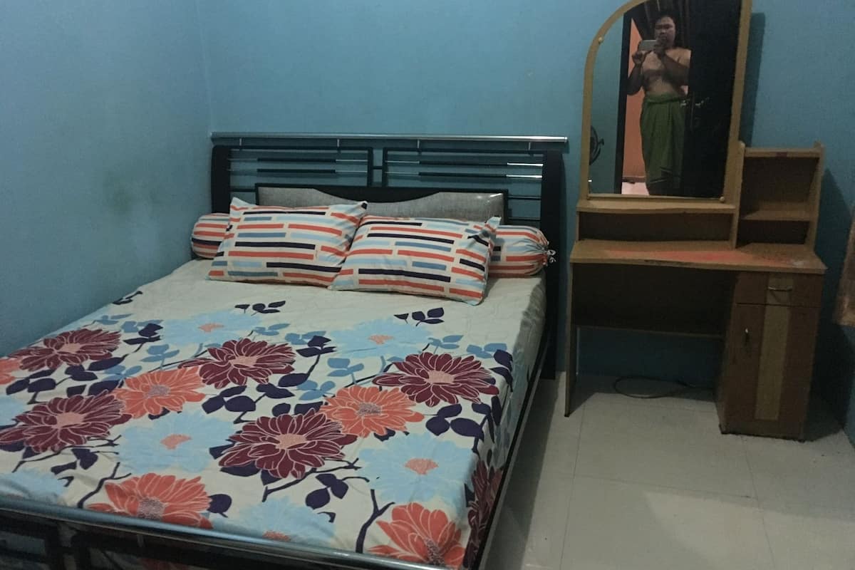 Una cama con ropa de cama floral, un cabecero de madera y un espejo encima.