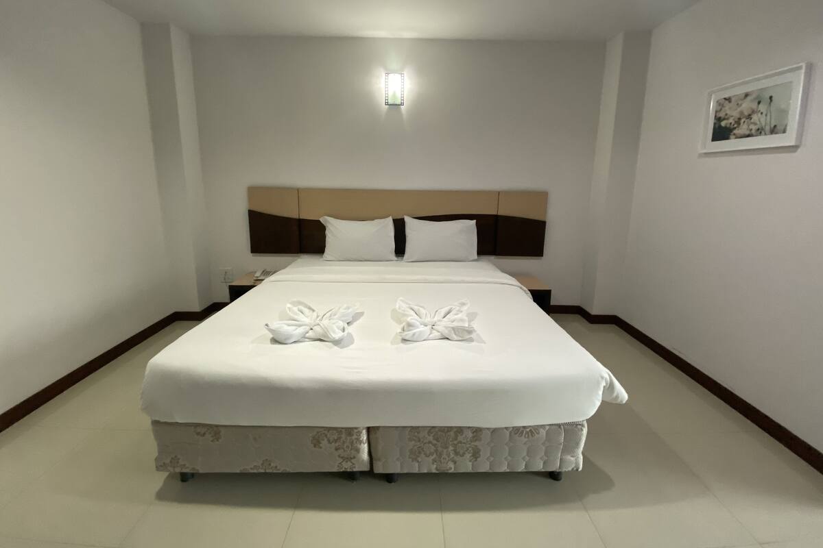 A neatly made double bed with a headboard, a bedside table, and a wall-mounted light fixture.