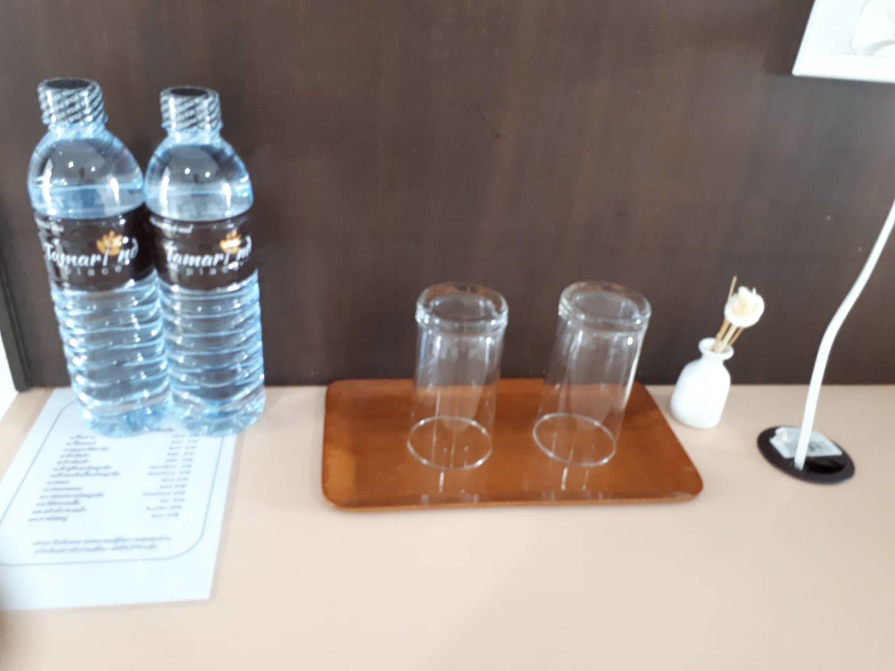 Una bandeja marrón con dos botellas de agua y tres vasos.