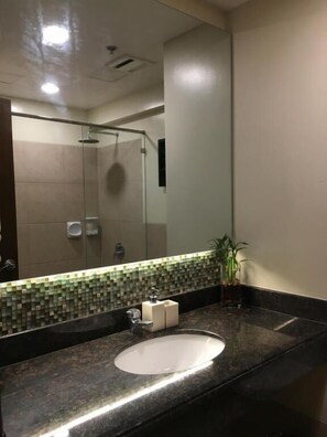 A modern bathroom with a large mirror, a sink, and a shower. - Outlook Ridge Residences N-206 (Baguio)