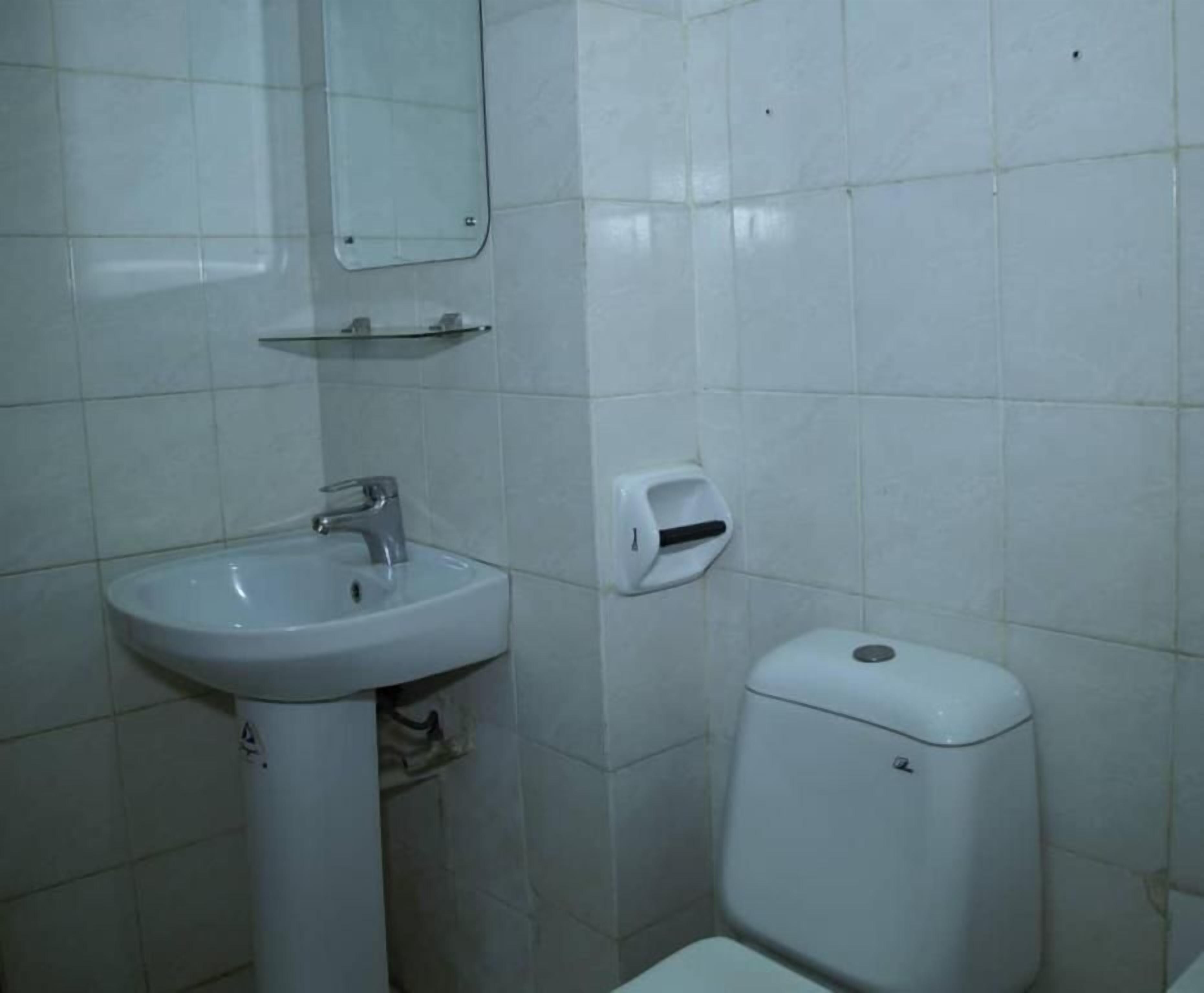 Une salle de bain avec un lavabo blanc, un miroir et des toilettes.