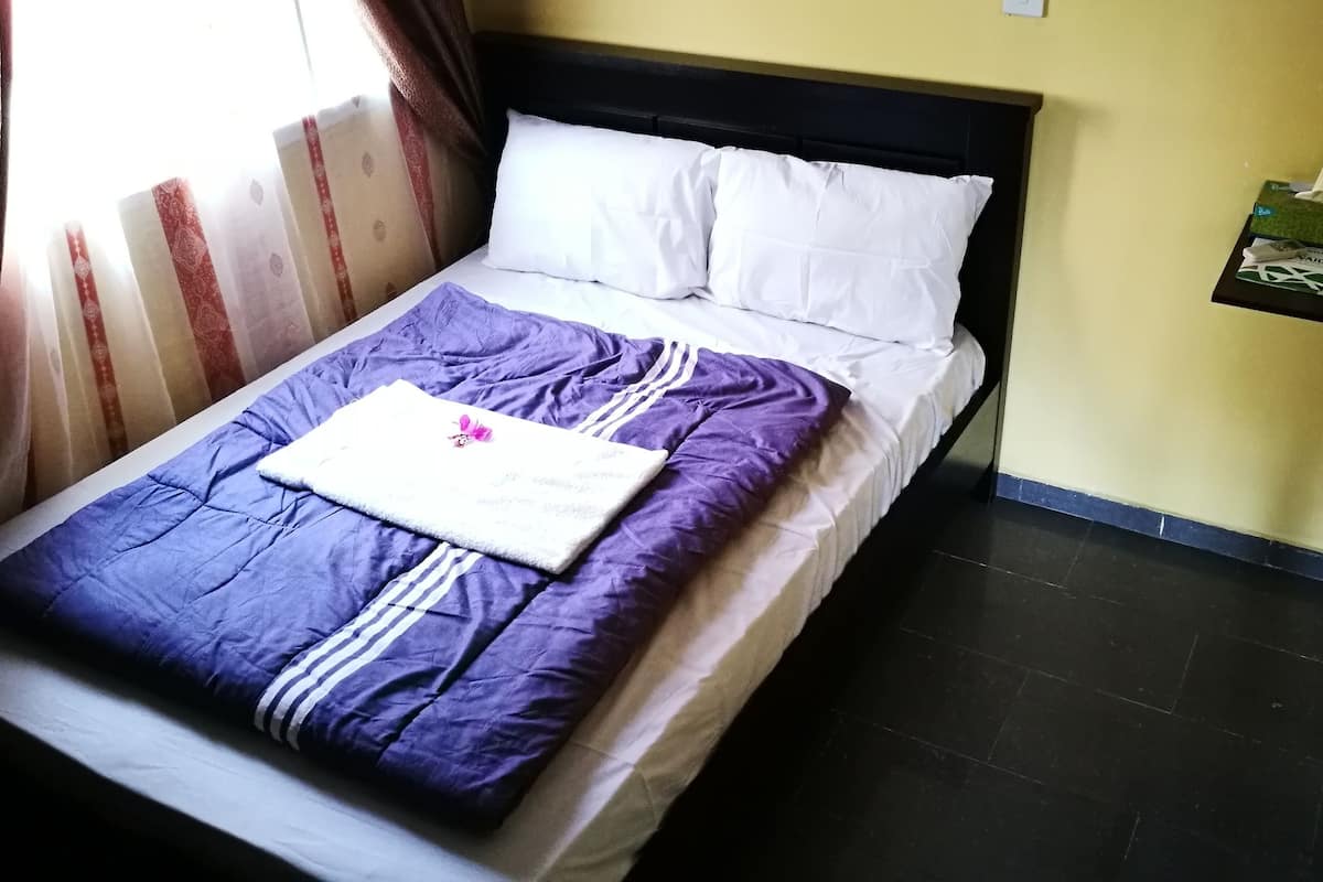 A neatly made bed with a purple and white duvet, white pillows, and a small decorative item on the bed.