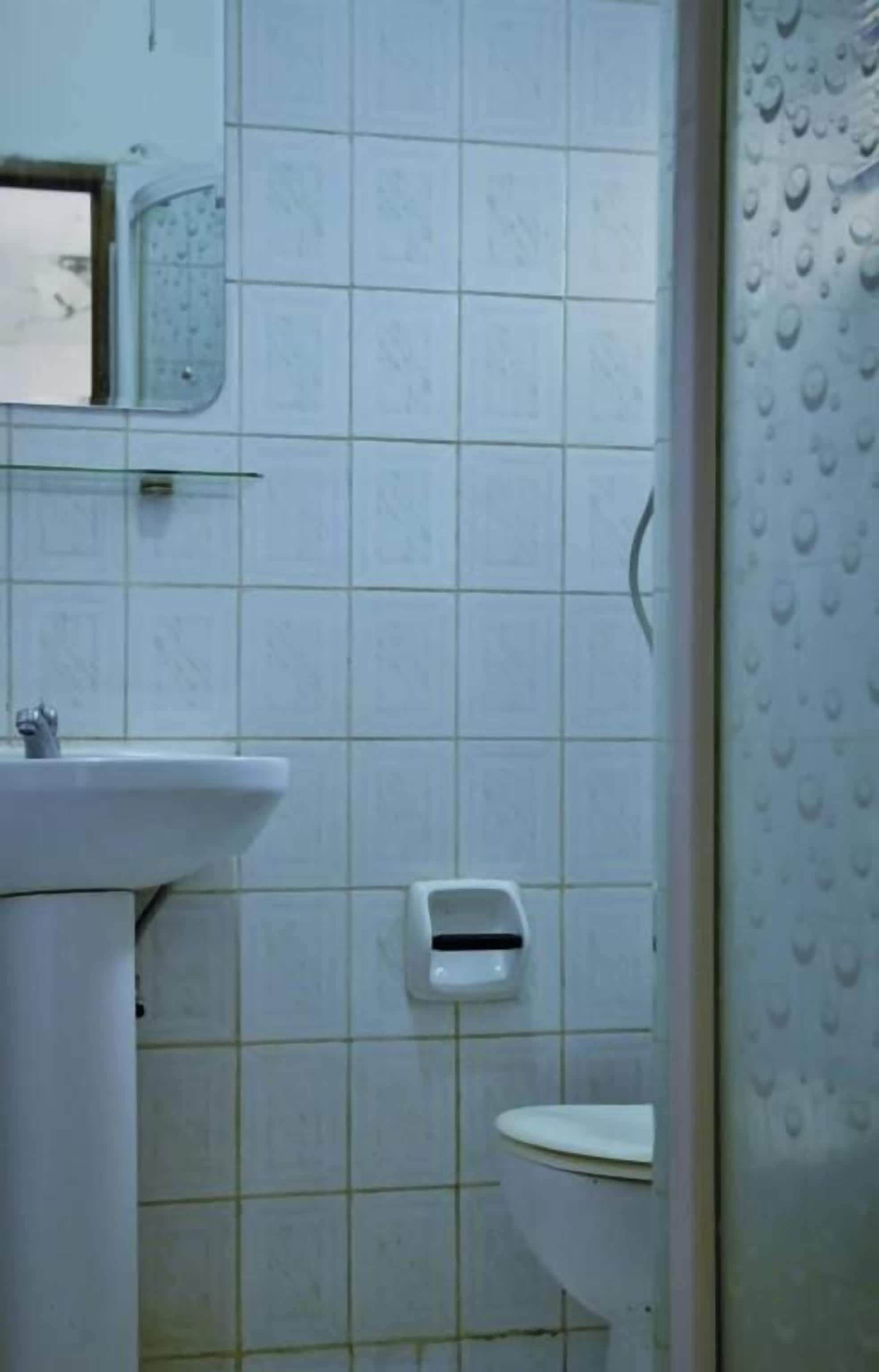 A bathroom with a sink, toilet, and a soap dispenser on the wall.