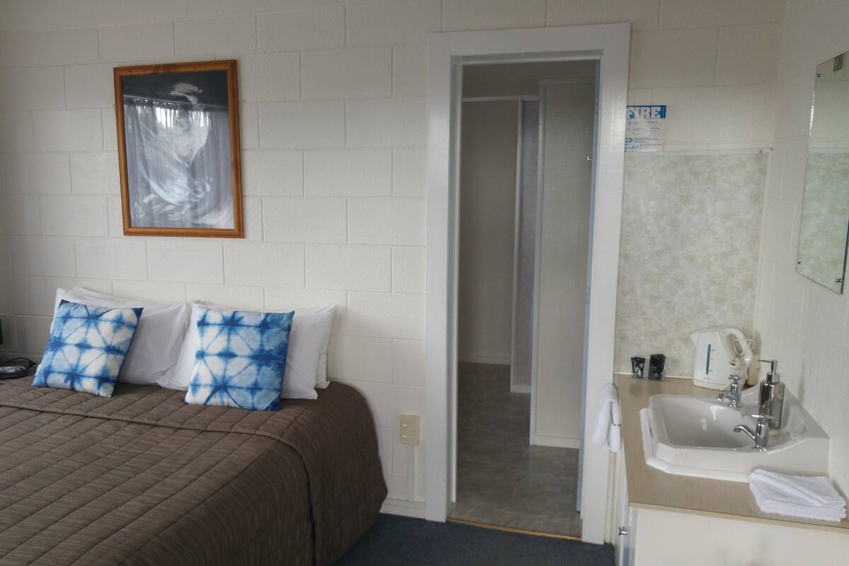 A hotel room with a bed, a bathroom, and a door leading to another room.