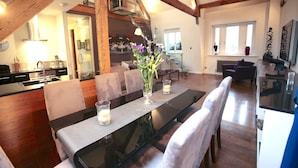 A modern dining area with a glass table, cushioned chairs, and a vase with flowers. - Tsq Whitehall (London)