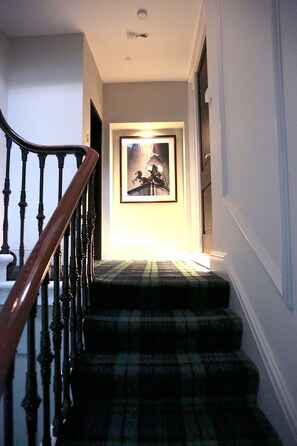 A staircase with a wooden handrail and a plaid carpet. - Tsq Whitehall (London)