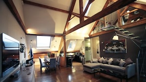 A spacious living area with a high ceiling, wooden beams, a dining area, and a kitchen. - Tsq Whitehall (London)