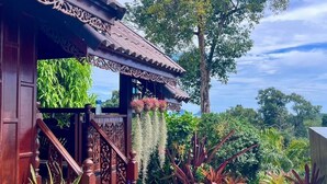 A traditional wooden building with intricate carvings, a staircase, and a variety of potted plants. - Klong Muang Seaview (Krabi)