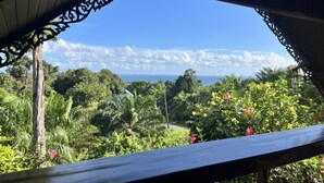 A view from a covered area with a wooden railing, overlooking a lush landscape with dense vegetation and a clear sky. - Klong Muang Seaview (Krabi)