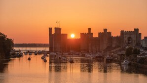 Un castillo histórico con un foso y barcos al atardecer.