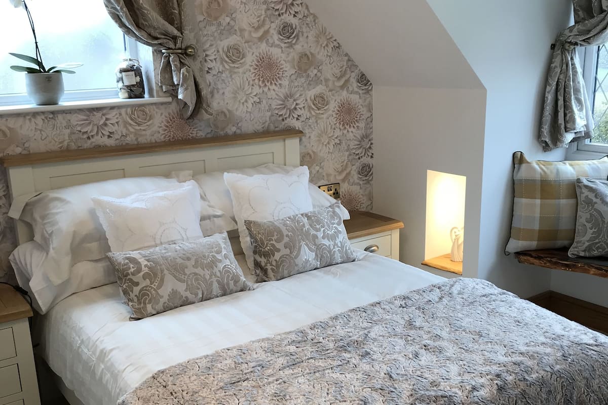 A bedroom with a bed, nightstands, a lamp, and a window with curtains.
