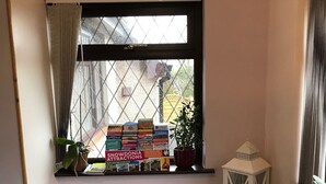 A cozy reading nook with a window, a shelf with books, a potted plant, and a lantern. - Lon Y Traeth Bed & Breakfast (Pentraeth)