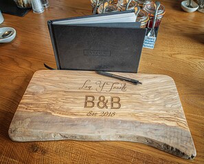 A wooden cutting board with engraved text and a pen on it. - Lon Y Traeth Bed & Breakfast (Pentraeth)