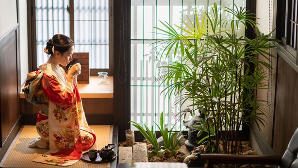 Perinteinen japanilainen huone, jossa on tatamimatto, shoji-liukuovi, bonsaipuu ja teekuppisetti.