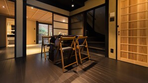 Una habitación japonesa tradicional con suelo de tatami, una mesa baja con sillas y puertas correderas.