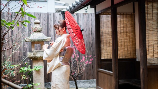 Perinteinen japanilainen puutarha, jossa on kivilyhty, puinen aita ja liukuovilla varustettu rakennus.