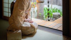Perinteinen japanilainen huone, jossa on tatamimatto, shoji-liukuovi ja näkymä puutarhaan liukuoven kautta.