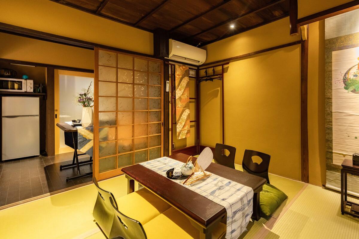 A traditional Japanese room with tatami flooring, a low table with a tea set, and sliding doors.
