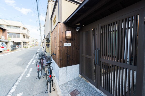 A bicycle parked outside a building with a wooden facade and a metal gate. - KumoMachiya Benzaiten (Kyoto)