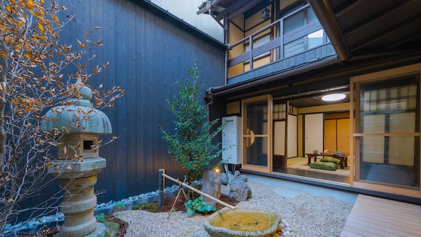 Een traditionele Japanse tuin met een stenen lantaarn, een kleine boom en een stenen waterbassin.