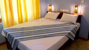 A bed with a striped bedspread, two bedside lamps, and a window with yellow curtains.