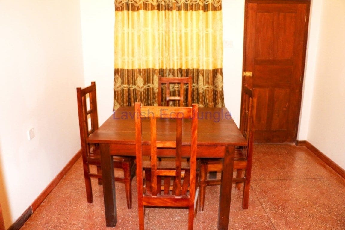 Un'area pranzo con tavolo e sedie in legno, una tenda e una porta in legno.