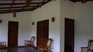 A room with four wooden chairs, a wooden door, and a wooden ceiling.