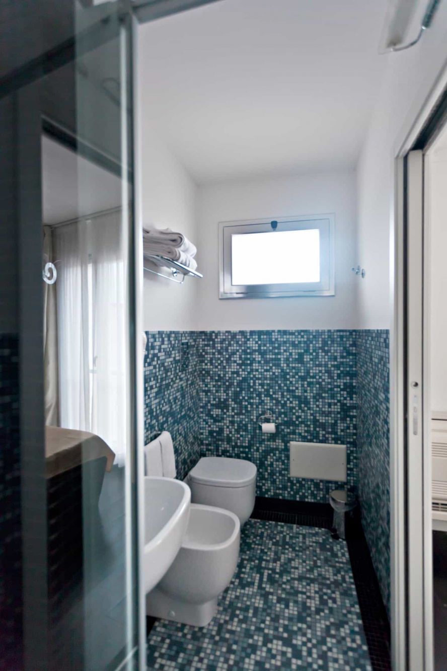 A bathroom with a tiled floor, a toilet, a bidet, and a shower area.
