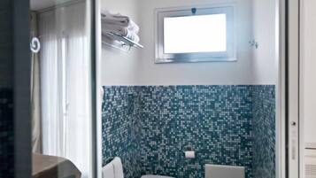 A bathroom with a tiled floor, a toilet, a bidet, and a shower area.