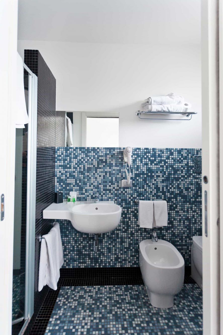 A bathroom with a white sink, a bidet, and a tiled backsplash.